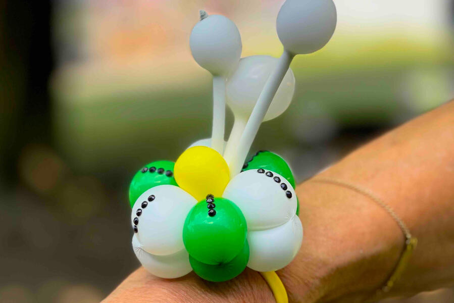 Sculpture de ballons Un bracelet fleur en ballons autour d'un poignet réalisé pendant un festival à l'extérieur.