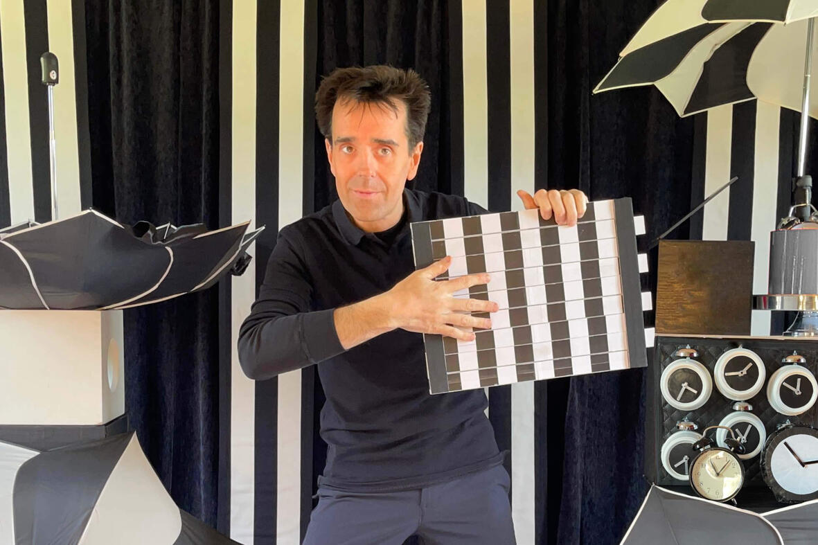 TacticOptik Monsieur Fred sur scène, réalisant un numéro de magie et d’illusion d’optique devant un décor en noir et blanc
