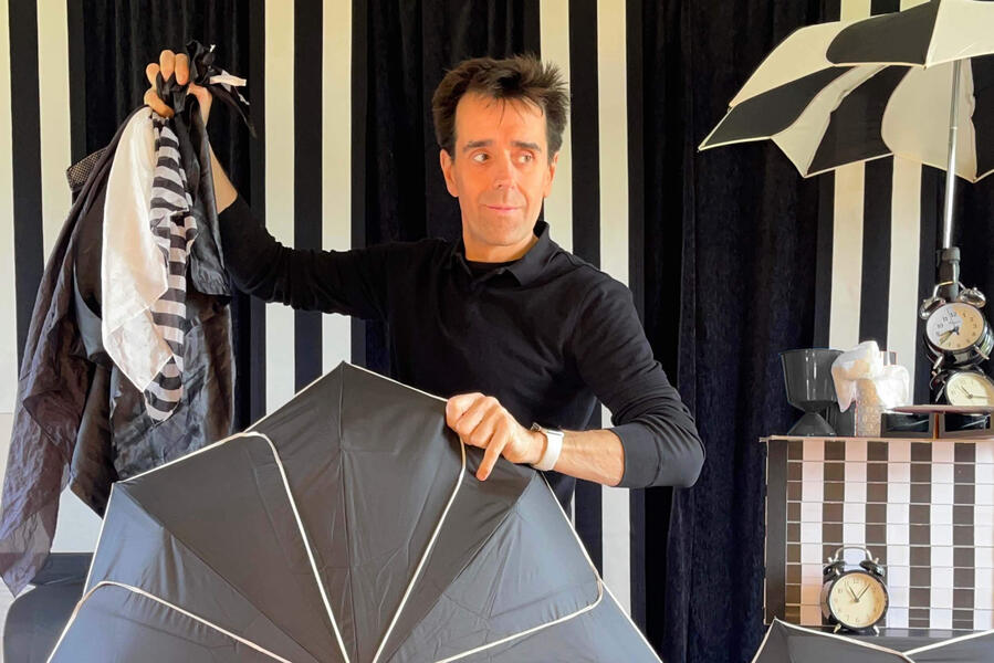 Monsieur Fred présente un une montagne de foulard en noir et blanc et sort plusieurs réveils et un parapluie géant sous les yeux du public lors d'un arbre de Noël pour une mairie dans la somme.