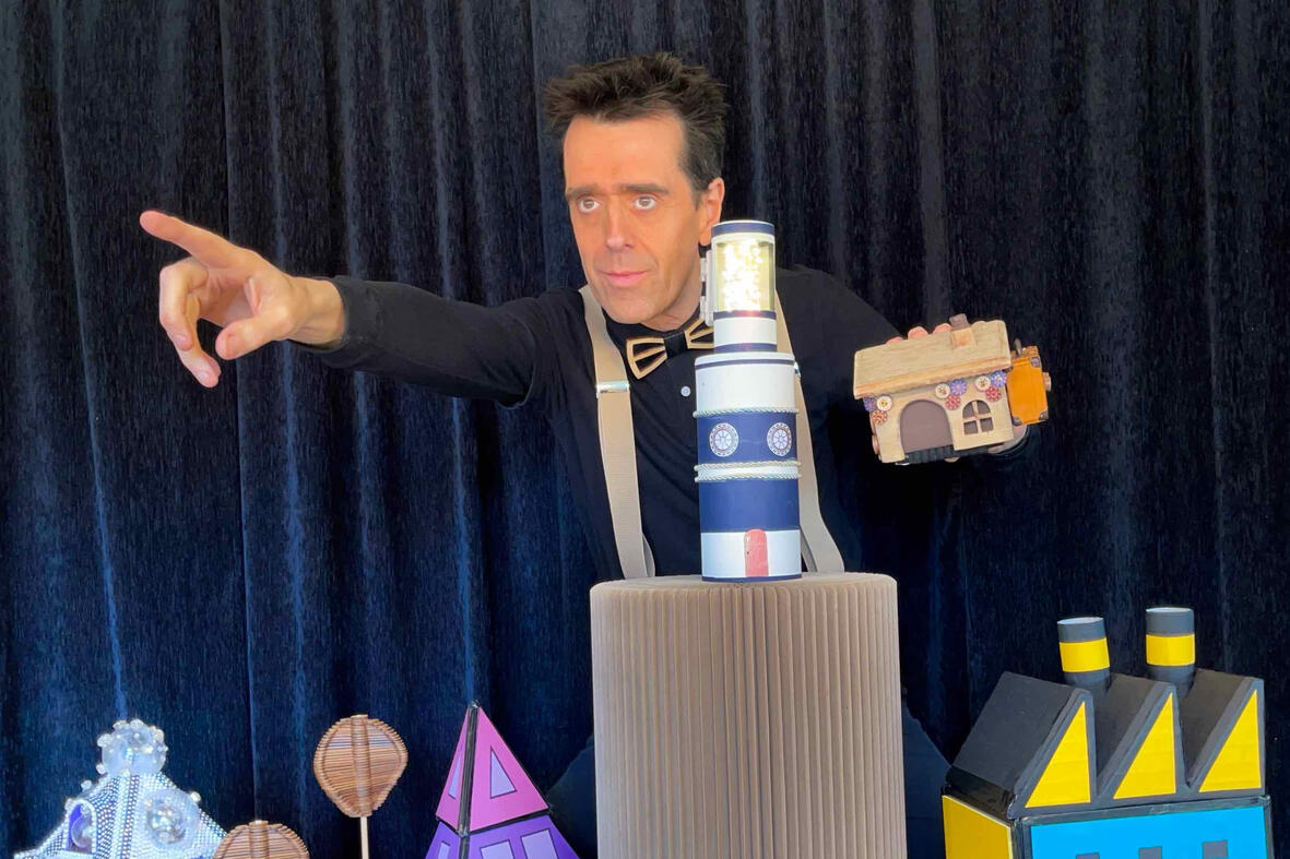 Risque-Tout Photo du spectacle “Risque-Tout” : Monsieur Fred anime la scène avec la petite maison, l’île et le personnage principal devant un public d’enfants.