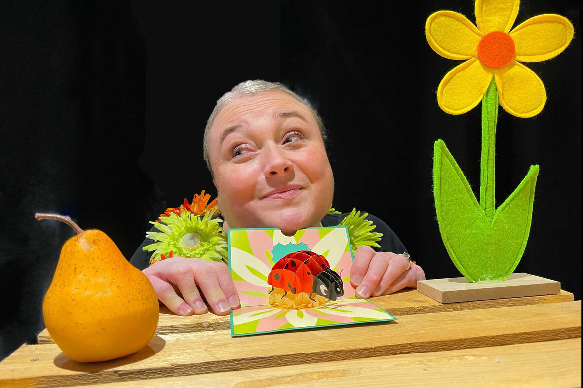 Spectacle j'me cache ! Aurore en pleine représentation, utilisant ses accessoires et personnages dans un décor chaleureux pour captiver le jeune public.