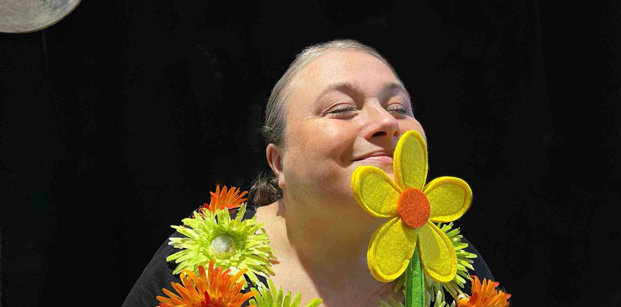 Spectacle j'me cache ! Aurore la conteuse sur scène, entourée de ses personnages et accessoires dans un décor en bois fleuri pendant une représentation.